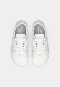 Baltas sporta apavi ar teksturētu virsmu, sasienamā dizaina un mīkstinātu apkaklīti. Iekļauj Reebok zīmola nosaukumu uz mēles un iekšējās zoles.