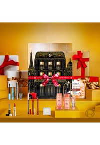 Geschenkset mit schwarzer Schachtel, illustriert mit einem Pariser Gebäude, goldfarbenen Akzenten, roten Bändern und einer Auswahl an L'Oréal-Schönheitsprodukten in pastellfarbener Verpackung.