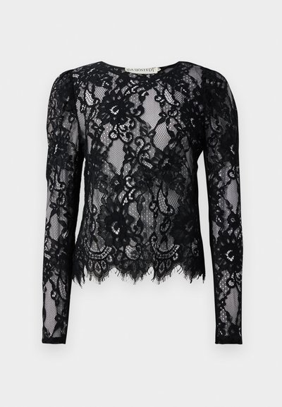 Blouse en dentelle noire à manches longues avec des motifs floraux, ourlet en dentelle, et col rond.