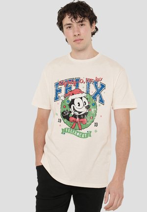 Young man wearing a beige t-shirt with a festive Felix the Cat graphic and the text "Righty-O, ho ho" on a plain background.