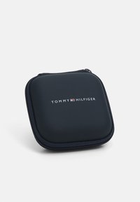 Tommy Hilfiger sort lynlåsetui med afrundede kanter. Glat tekstur, brandlogo trykt på forsiden, designet til bærbarhed.
