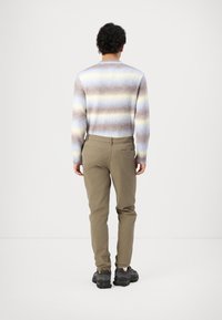 Knit sweater with horizontal stripes in beige, blue, and yellow; paired with khaki, slim-fit pants and black athletic shoes.