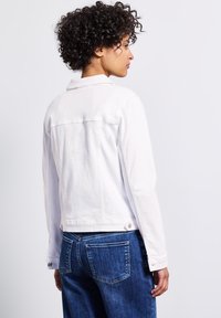 Biała kurtka dżinsowa o dopasowanym fasonie, z ostrym kołnierzem, długimi rękawami i pojedynczym zapięciem na guzik w talii.