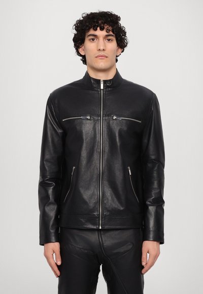 Schwarze Lederjacke mit Stehkragen, silbernen Reißverschlusstaschen und einem schlanken Design. Sie verfügt über eine glatte Textur und eine figurbetonte Form.