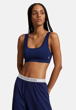 Marineblauer Sport-BH mit Rundhalsausschnitt und breiten Trägern. Hergestellt aus einem glatten Material, mit einem kleinen weißen Logo an der Seite.