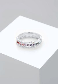 Anillo de plata con un diseño retorcido, que presenta piedras multicolores a lo largo de la banda. Acabado suave, forma circular y detalles de acento sutiles.