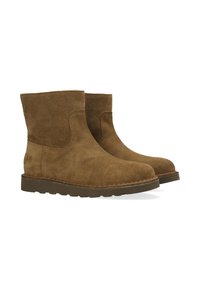 Botas de tobillo de ante marrón con suelas planas de goma oscura, punteras redondeadas y detalles cosidos, mostradas lado a lado sobre un fondo blanco.