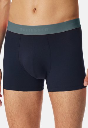 Marineblaue Boxershorts aus weichem Stoff, mit einem grauen gebrandeten Bündchen und einem körperbetonten Design. Glatte Textur mit minimalen Nähten.