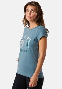 Blue short-sleeve t-shirt made of soft fabric with a graphic of mountains and trees, featuring "OUTDOOR EXPEDITION" text in green.