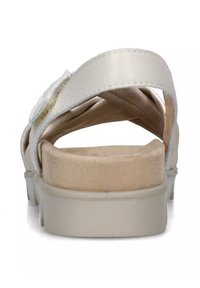 Sandalia de cuero blanca con correas cruzadas, plantilla de color beige suave y suela de goma gris clara. Presenta una textura suave y detalles de costura sutiles.