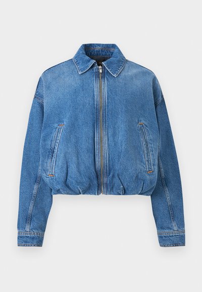 Veste en denim bleu à fermeture éclair avec col, manches longues, poches latérales et ourlet élastiqué, posée à plat sur un fond clair.