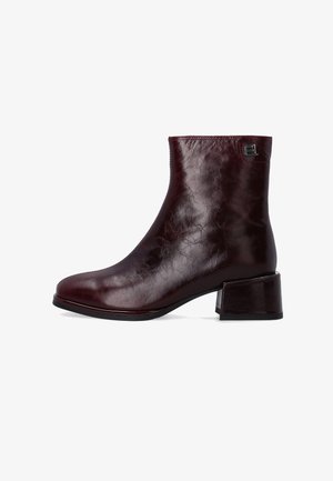 Bordowe skórzane botki za kostkę z okrągłym noskiem, gładką powierzchnią i słupkowym obcasem. Zawierają drobny metalowy detal z logo z boku.