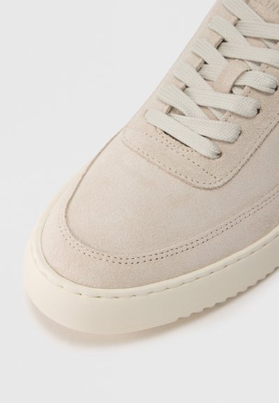 Αθλητικό παπούτσι από μπεζ σουέτ με λε ία επιφάνεια, διαθέτει κορδόνια στο ίδιο χρώμα και παχύ καουτσούκ πέλμα. Στρογγυλεμένη μύτη και διακριτικές ραφές.