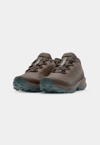 Braune Outdoorschuhe haben ein strukturiertes Synthetik-Obermaterial, eine verstärkte Zehenkappe und kontrastierende Türkis-Akzente an der Sohle und den Seitenstreifen.
