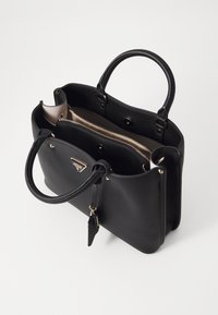 Sort lædertaske med dobbelte håndtag, beige inderside og guldfarvet hardware. Indeholder et rum med lynlås og logo-detalje.