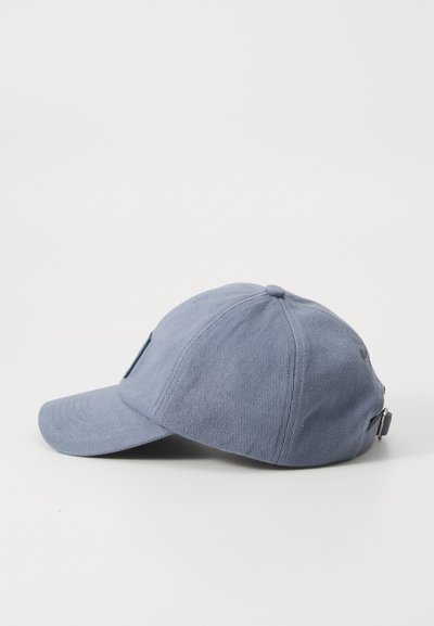 Casquette de baseball bleue avec une visière courbée, en tissu texturé, et une sangle ajustable à l'arrière. Présente un détail de logo sur le côté.
