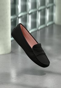 Svart läderloafers med en slät yta, med en rosa innersula och dekorativ söm längs kanten. Minimalistisk design, ingen synlig hårdvara.