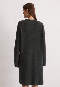 Robe à manches longues en tissu tricoté gris foncé, avec un col rond simple et une silhouette décontractée qui tombe au milieu de la cuisse.