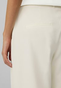 Crème-kleurige op maat gemaakte broek met een gladde textuur. Beschikt over een enkele achterzak en een schoon, minimalistisch ontwerp.