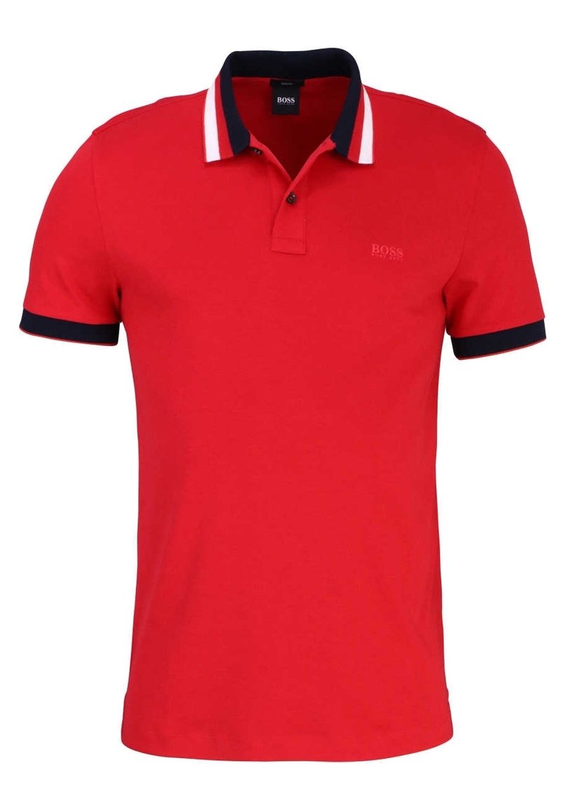 Rød polo shirt lavet af bomuld. Har en marineblå krave og manchetter med hvide striber. Lille prægede logo på venstre bryst. Korte ærmer.