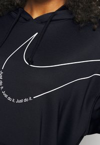 Sudadera negra de tela suave, con un destacado swoosh blanco de Nike y el texto "Just do it" repetido en un diseño curvo en la parte frontal.