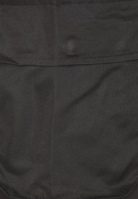 Zwarte stof met een gladde textuur, voorzien van een horizontaal zakontwerp aan de bovenkant en zichtbare stiksels langs de randen.