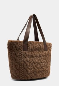 Borsa tote in finta pelliccia marrone con design a maglia a treccia testurizzata, dotata di manici in pelle marrone scuro. Ampia e morbida, con una forma strutturata.