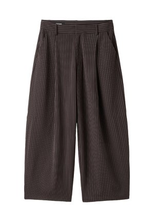Persoon draagt zwarte pantalon met fijne strepen, met hand in de zak en zichtbare blauwe cropped top taille.