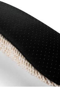 Czarna, teksturowana tkanina z delikatnym, kropkowanym wzorem otacza miękką, kremową, wątkową strukturę. Oba materiały wyraźnie kontrastują ze sobą.