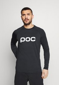 Långärmad svart skjorta med rund halsringning, prydd med en vit "poc"-logotyp på framsidan. Tillverkad av ett mjukt, stretchigt tyg.