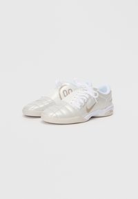 Sapatos de desporto prateados metálicos com atacadores brancos, apresentando detalhes acolchoados e um pequeno logótipo dourado. Acentos em azul claro no colarinho.