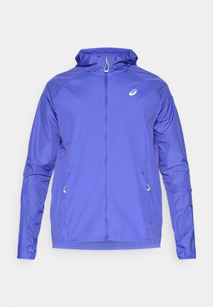 Ελαφρύ μωβ μπουφάν με φερμουάρ μπροστά, κουκούλα και ανακλαστικό λογότυπο. Διαθέτει ελαστικές μανσέτες και πλευρικές τσέπες. Απαλή, ανθεκτική στο νερό υφή.