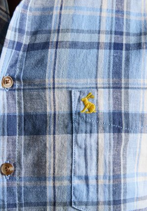 Blau-weiß kariertes Hemd mit braunen Knöpfen und einer Brusttasche, bestickt mit einem kleinen gelben Hasen.