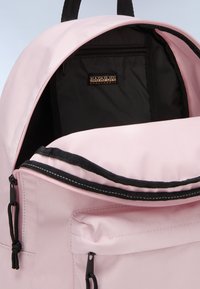 Zaino rosa con dettagli in cerniera nera e tracolle, dotato di una tasca interna con cerniera e tessuto texture. L'interno è nero.