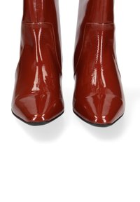 Glanzende rode enkelboots met een puntige neus en een gladde textuur. De laarzen hebben een slanke silhoutte met minimale stikseldetails.