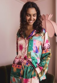 Buntes Seiden-Pyjama-Set mit Sonne- und Sternmustern, in einem rosa-grünen Farbschema, mit einem knöpfbaren Oberteil und Hosen mit elastischem Bund.