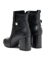 Czarne skórzane botki za kostkę z okrągłym noskiem, blokowym obcasem, bocznym zamkiem błyskawicznym oraz ozdobnym paskiem z okrąłym metalowym akcentem.