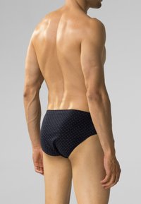 Ciemnoniebieskie kąpielówki z subtelnym białym wzorem geometrycznym, wykonane z gładkiego materiału, z niskim stanem i dopasowanym krojem.