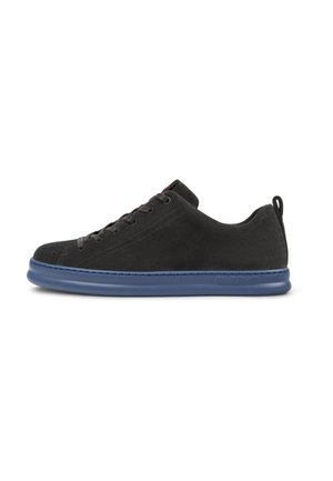 Black suede sneaker featuring a blue rubber sole, round toe, six eyelets for laces, and a rear pull tab. Clean, minimalistic design.