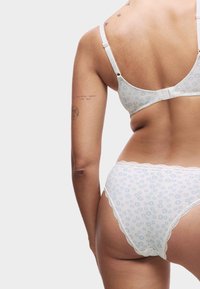 Bralette à motifs floraux bleu clair avec culottes assorties et bordures en dentelle, fabriqués en tissu doux, montrant une vue de dos.