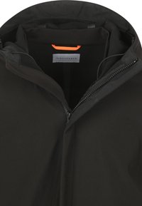 Zwarte jack met een gedeeltelijk open rits aan de voorkant, waarbij een zwarte voering en een beige label met een kleine oranje lus erboven zichtbaar zijn.