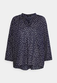 Blusa blu navy con vestibilità ampia, maniche lunghe, scollatura a V e motivi floreali bianchi sparsi. Realizzata in tessuto leggero e trasparente.