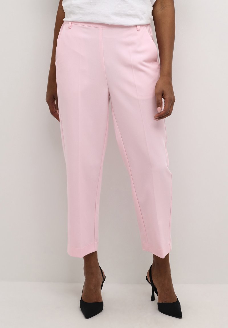 Roze op maat gemaakte broek met een gladde textuur, toelopende pijpen en zijzakken, gecombineerd met zwarte puntige hakken.