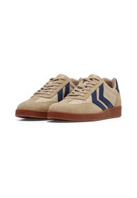Beige suede sneakers with blue accents and textured side stripes. Features a brown rubber sole and beige laces. Subtle logo detail on the side.