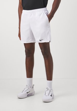 Weiße Sportshorts mit einem elastischen Bund und seitlichen Taschen; mit einem schwarzen Nike-Logo am linken Saum; glatte Textur.