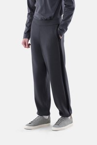 Dunkelgraue Fleece-Jogginghosen mit entspanntem Schnitt, elastischem Bund und Seitentaschen, kombiniert mit grauen Sneakers mit schlichter Gestaltung.