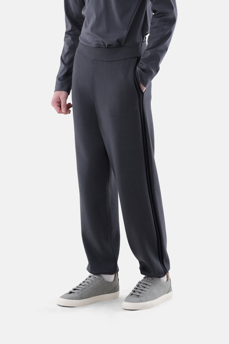 Dunkelgraue Fleece-Jogginghosen mit entspanntem Schnitt, elastischem Bund und Seitentaschen, kombiniert mit grauen Sneakers mit schlichter Gestaltung.