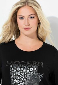 Czarny t-shirt z motywem srebrnej pantery ozdobionym cyrkoniami oraz napisem "MODERN." Gładka tkanina, okrągły dekolt i luźny krój.