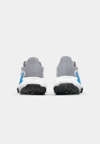 Baskets de sport grises avec des accents bleus, présentant un col rembourré et des semelles texturées adaptées à l'adhérence. Talon renforcé et matériau en mesh.