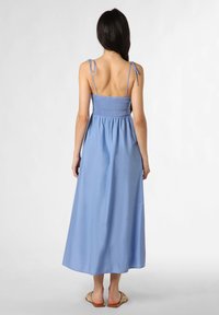 Maxikleid in Hellblau, mit verstellbaren dünnen Trägern, gesmoktem Oberteil und fließendem Rock. Der Stoff wirkt leicht und glatt.